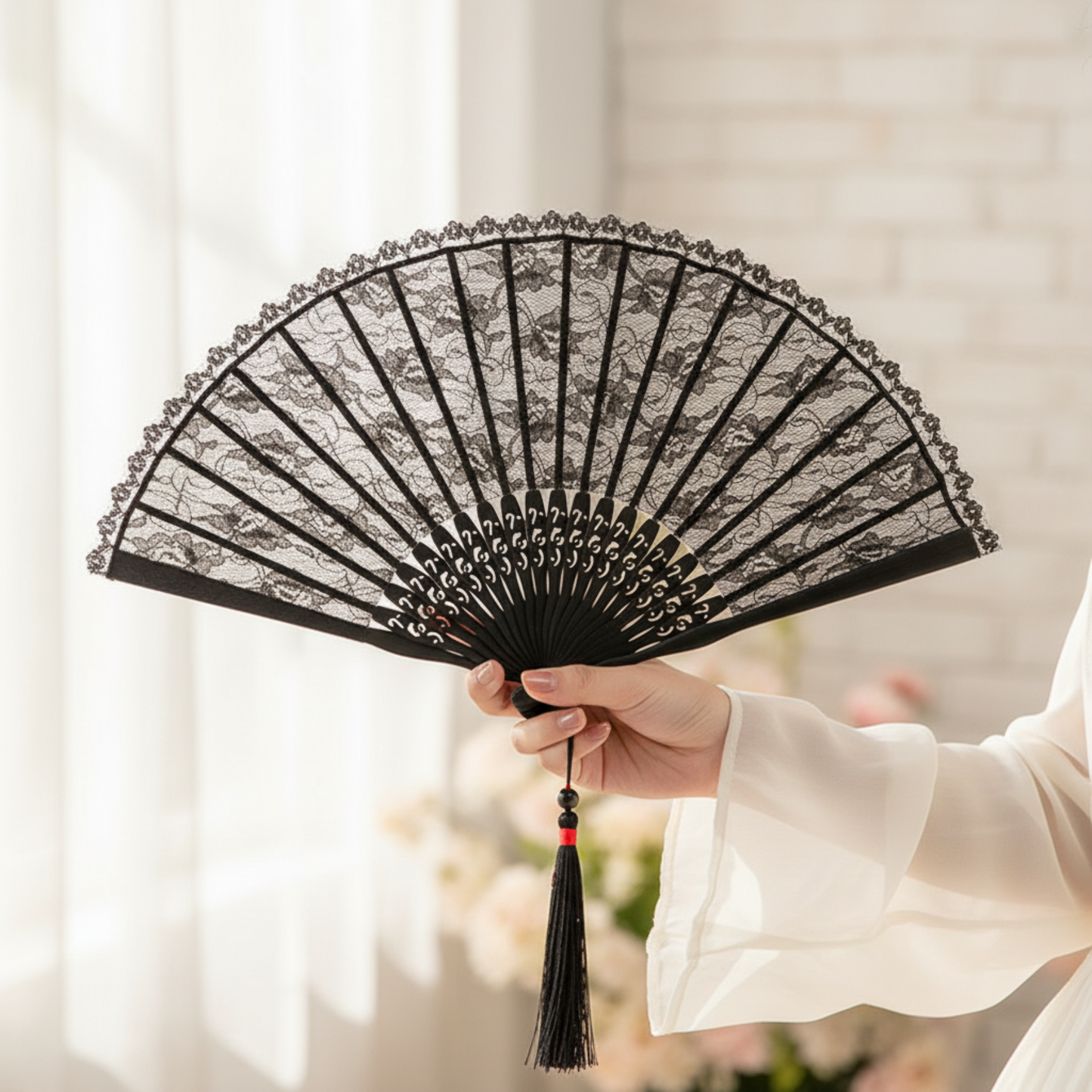 Hand holding black lace fan on white fabric
