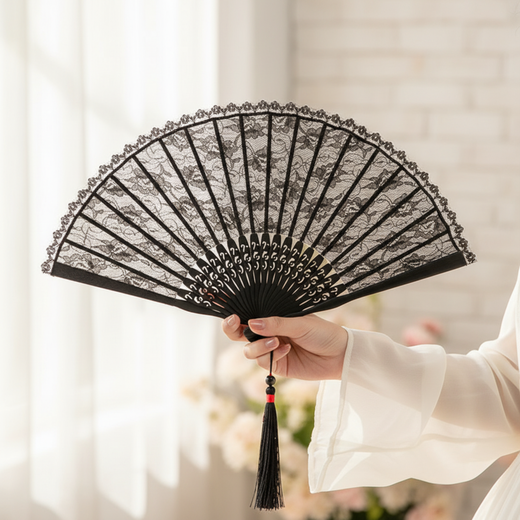 Hand holding black lace fan on white fabric