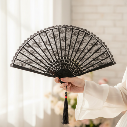 Hand holding black lace fan on white fabric