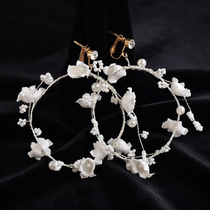 Flower crown headband and hoop earrings flat lay on black background