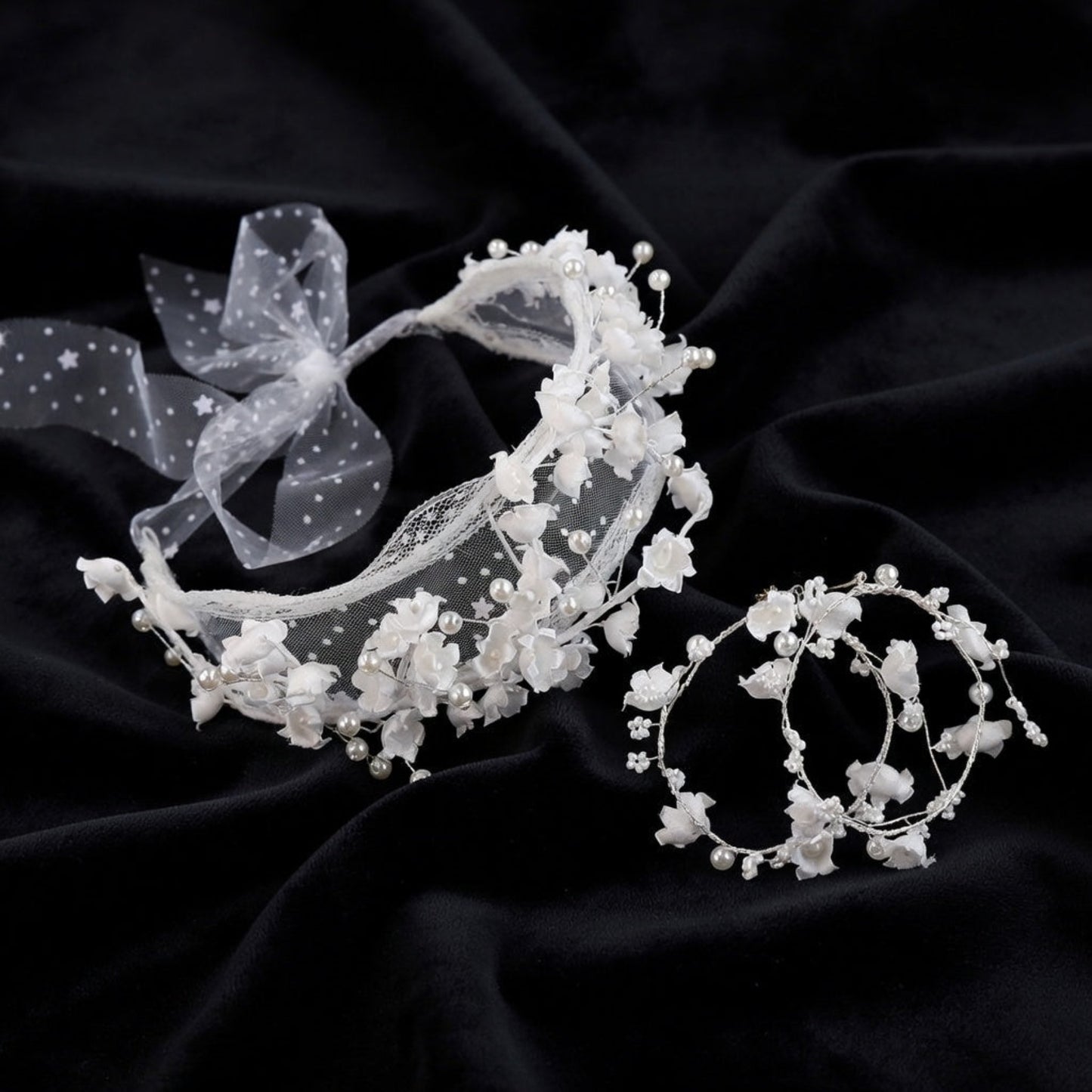 White flower crown bridal headband and earrings set flat lay on black silk