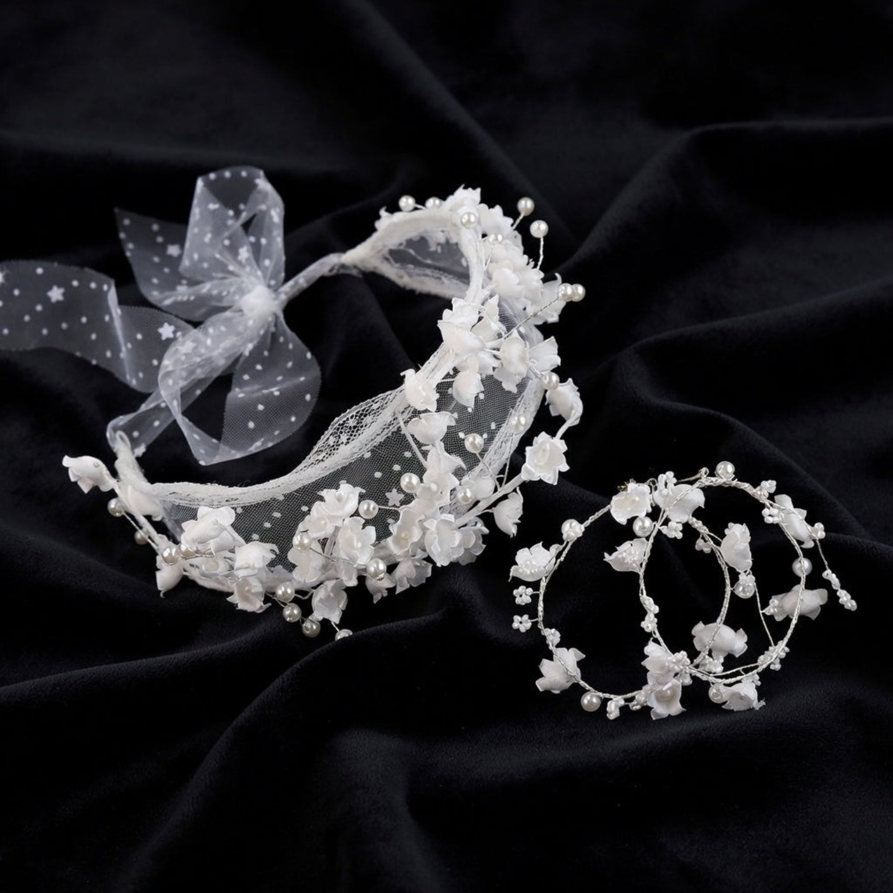White flower crown bridal headband and earrings set flat lay on black silk