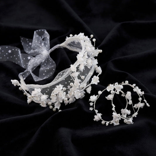White flower crown bridal headband and earrings set flat lay on black silk