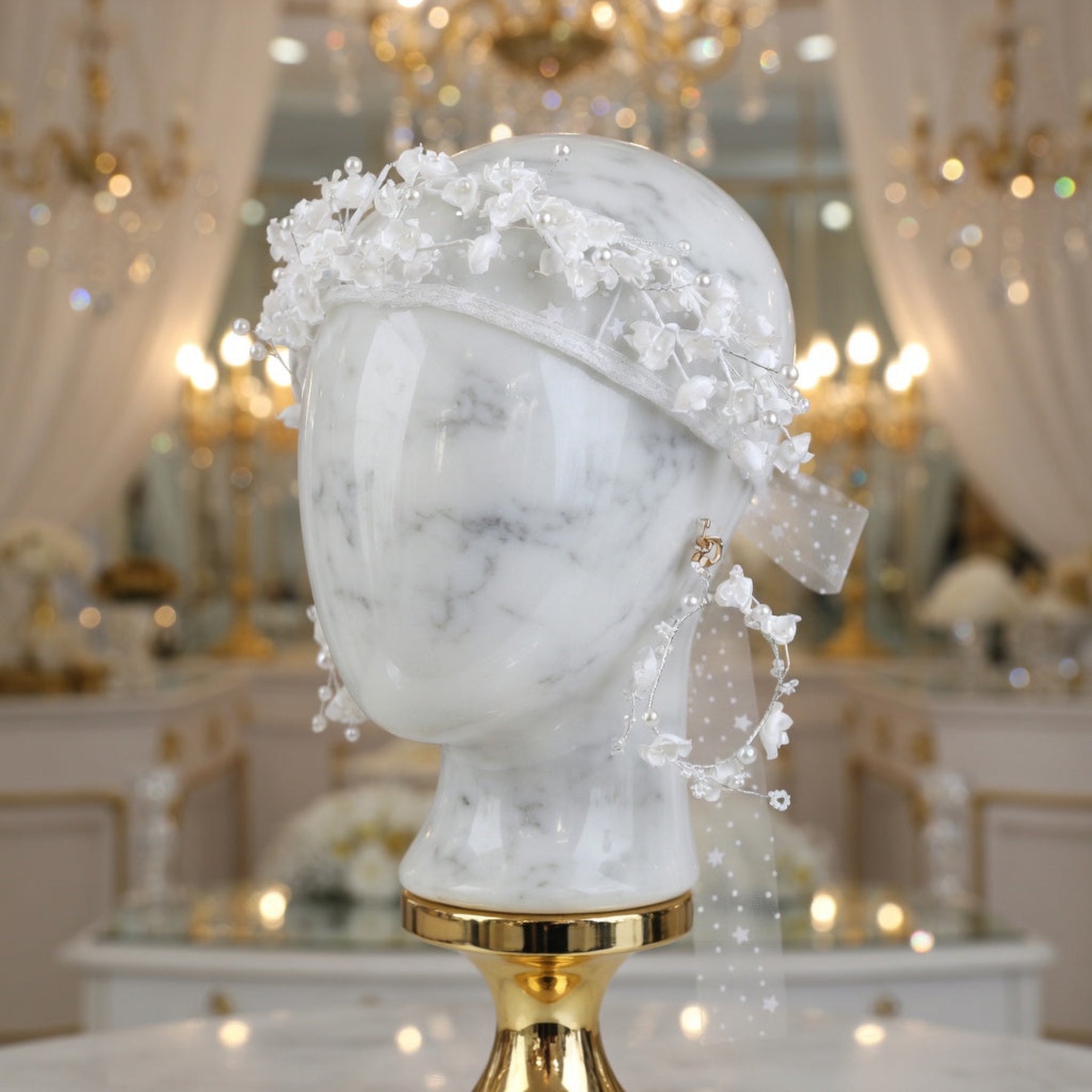 White flower crown headband on mannequin head under gold chandelier