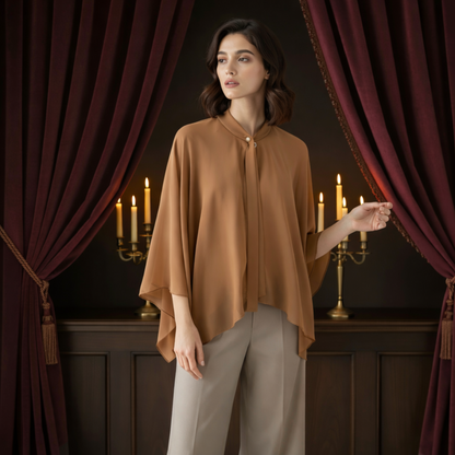Woman wearing beige chiffon poncho cape near curtains and candles