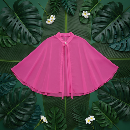 Pink chiffon poncho cape flat lay with tropical leaves