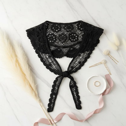 Black crochet lace shawl flat lay on white marble with ribbon