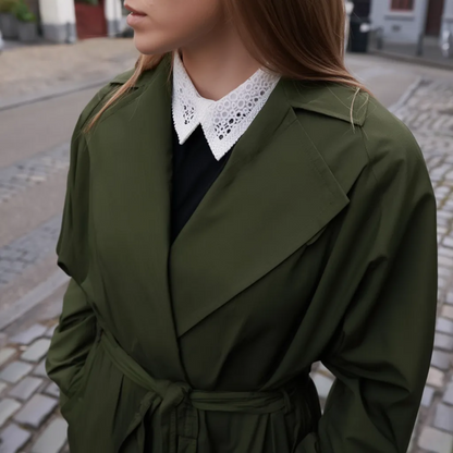 Woman wearing white lace collar with dark green coat on city street