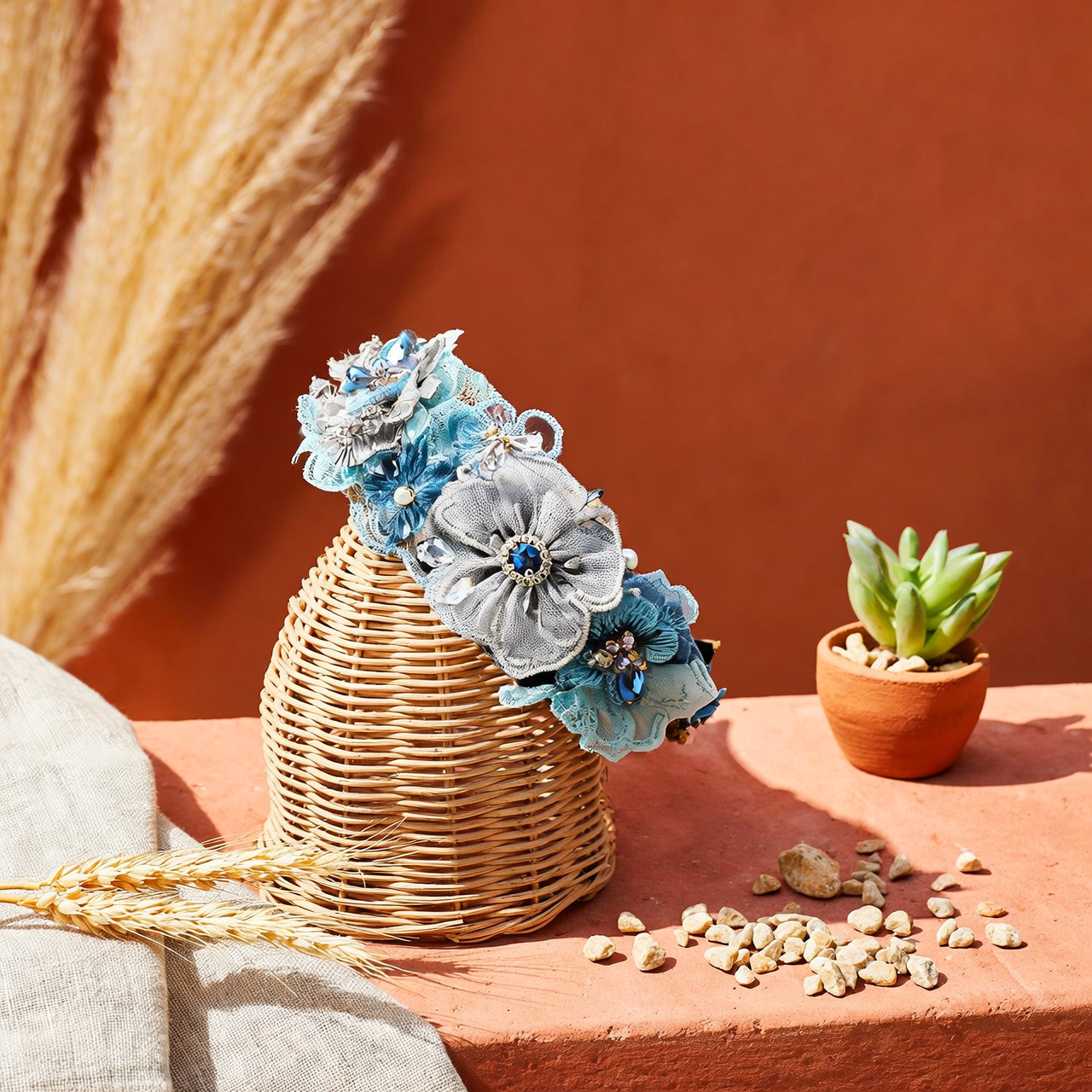 Blue floral lace headband on wicker stand with terracotta background