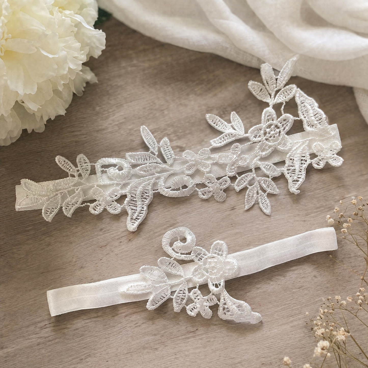 White lace bridal garter set flat lay on fabric