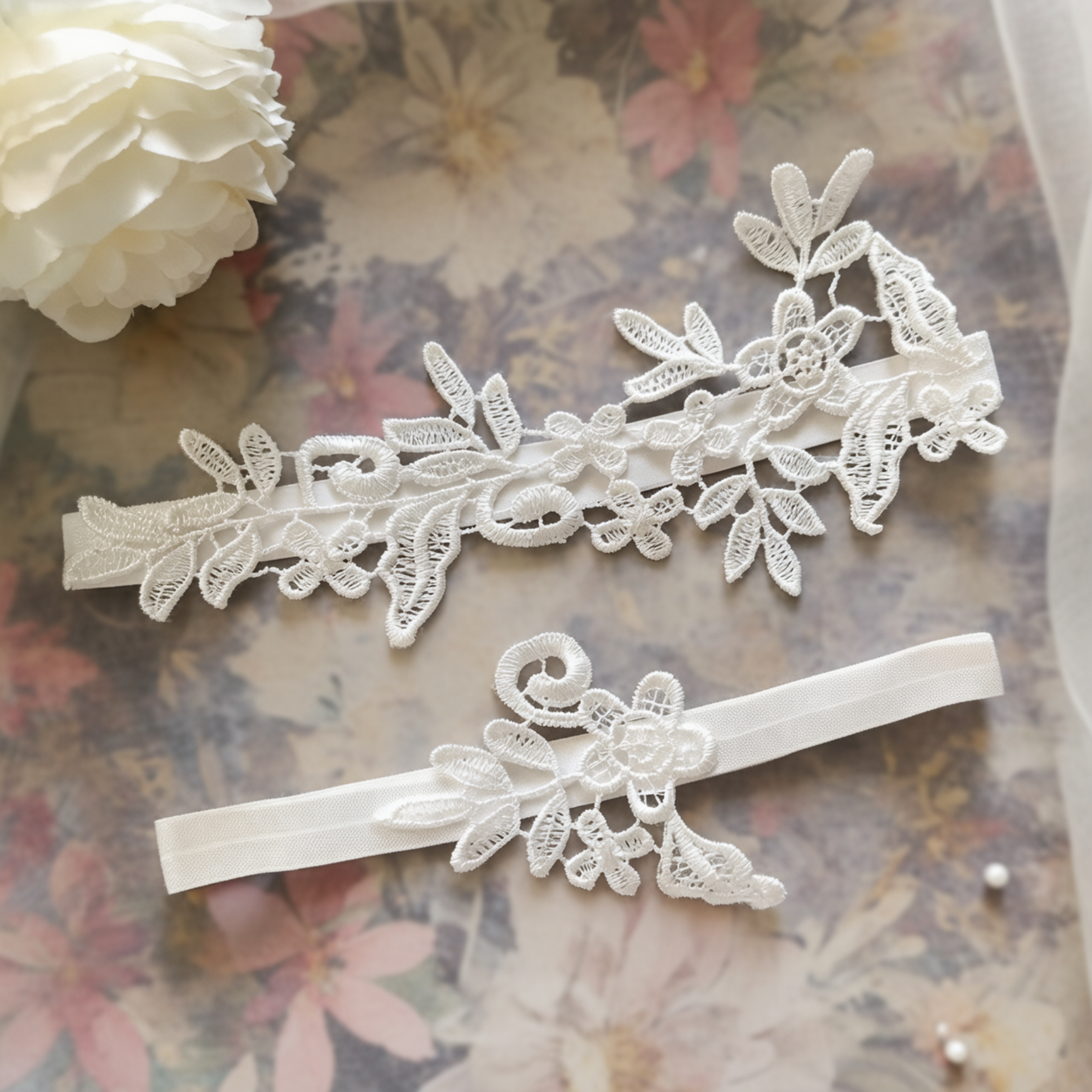 White lace bridal garter set flat lay on floral background