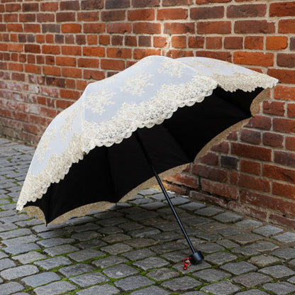 Black lace embroidery umbrella open against brick wall