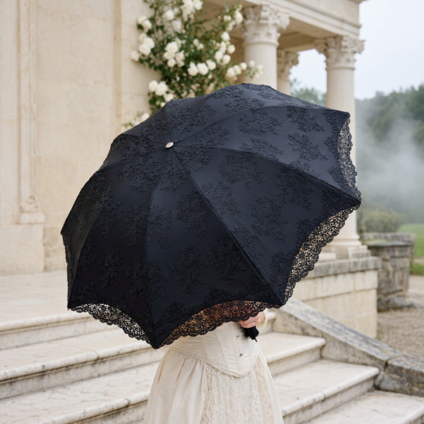 Black lace embroidery umbrella on building steps in fog