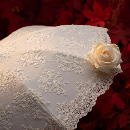 Close-up of white lace embroidery umbrella fabric with rose and red leaves
