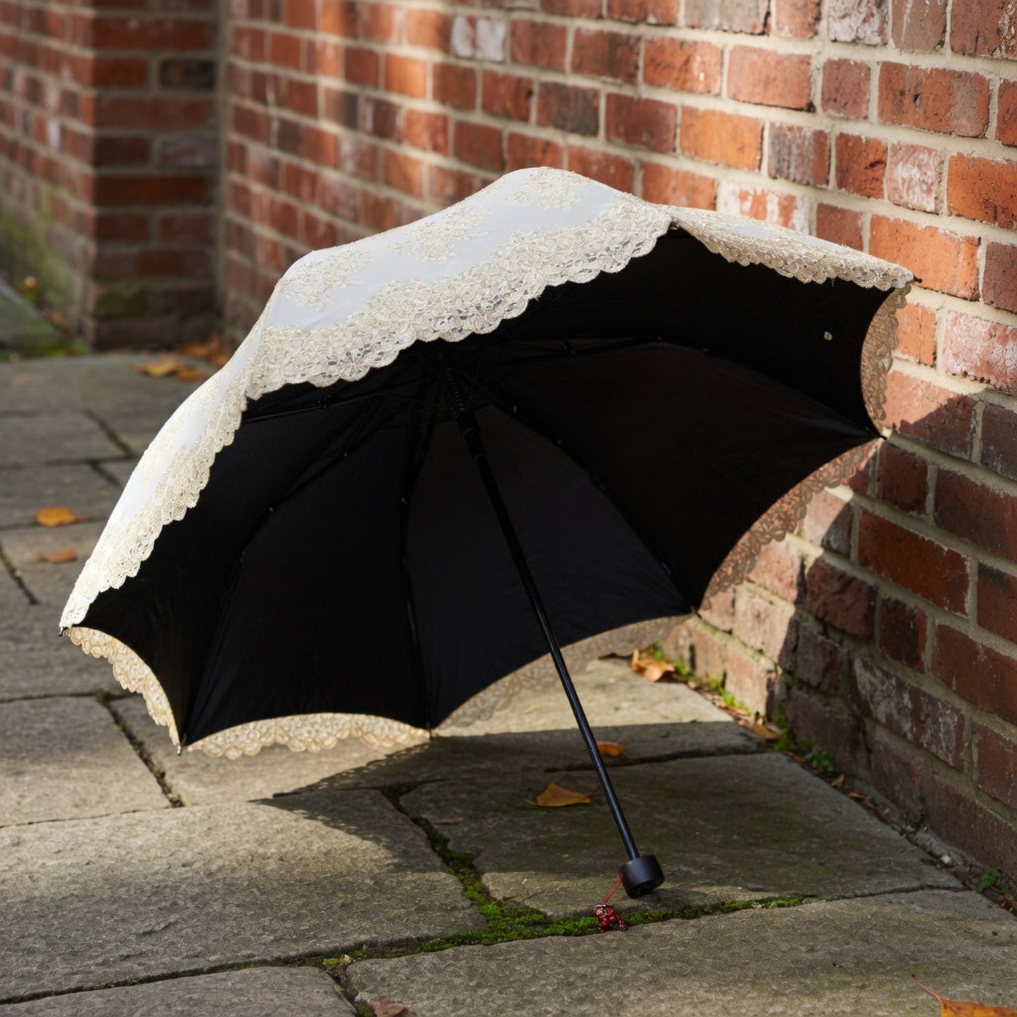White lace embroidery umbrella on cobblestone by brick wall