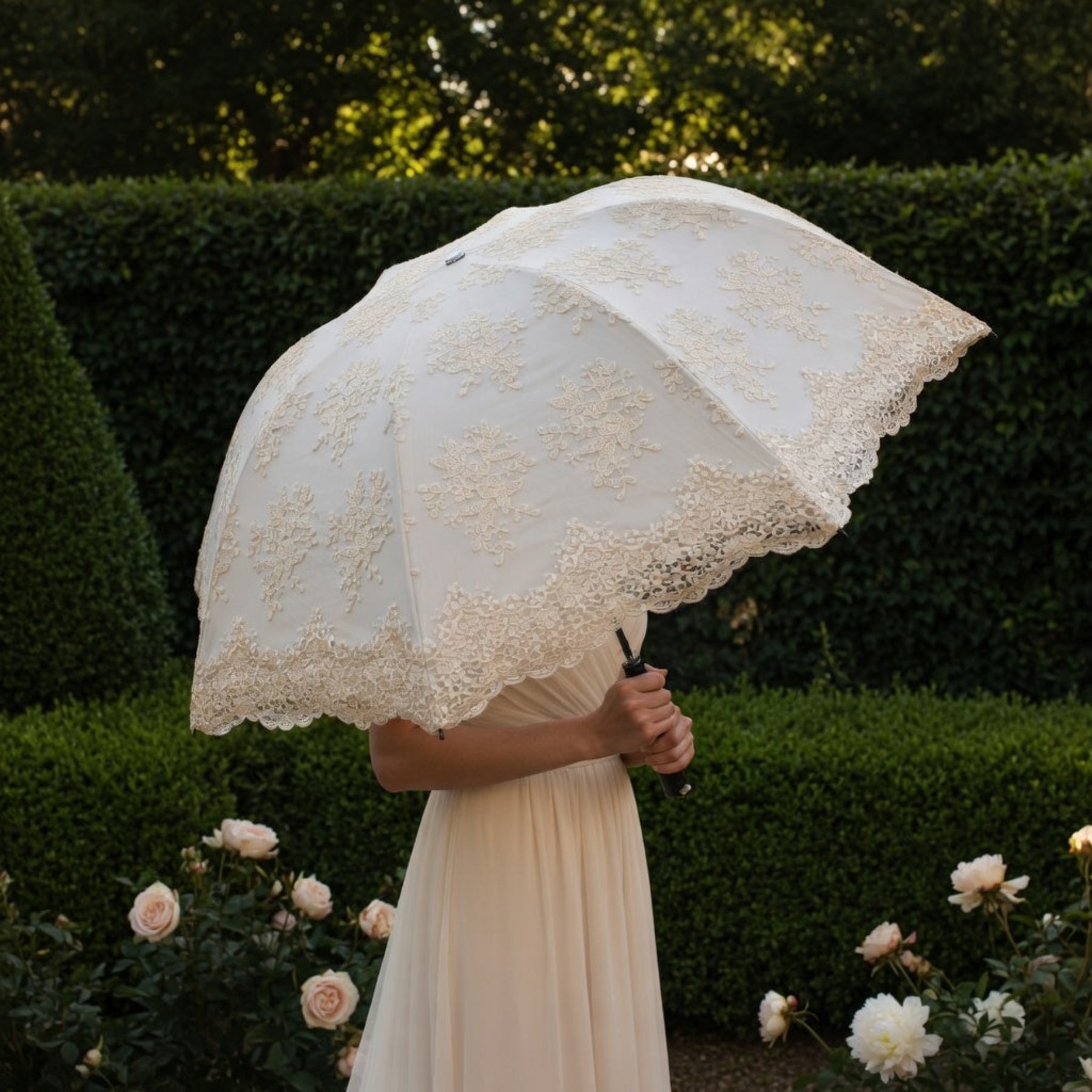 Woman holding white lace embroidery umbrella by hedge