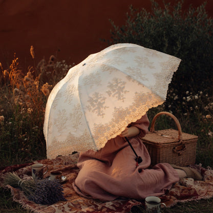 White lace embroidery umbrella with picnic basket at dusk