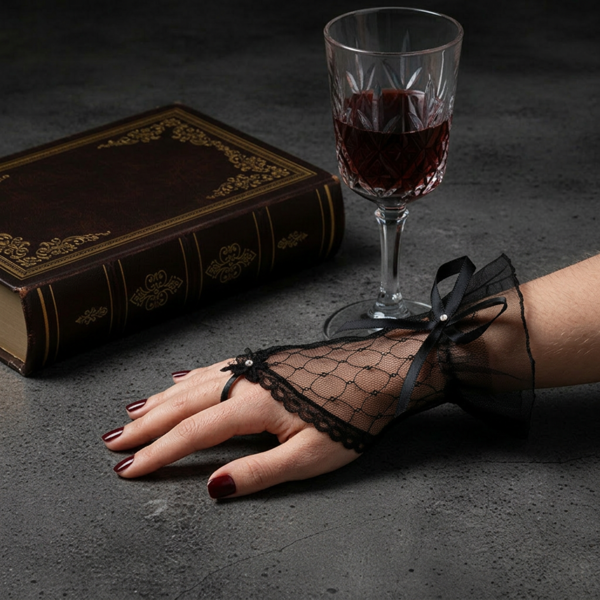 Black lace fingerless glove with rhinestone bow beside wine and book