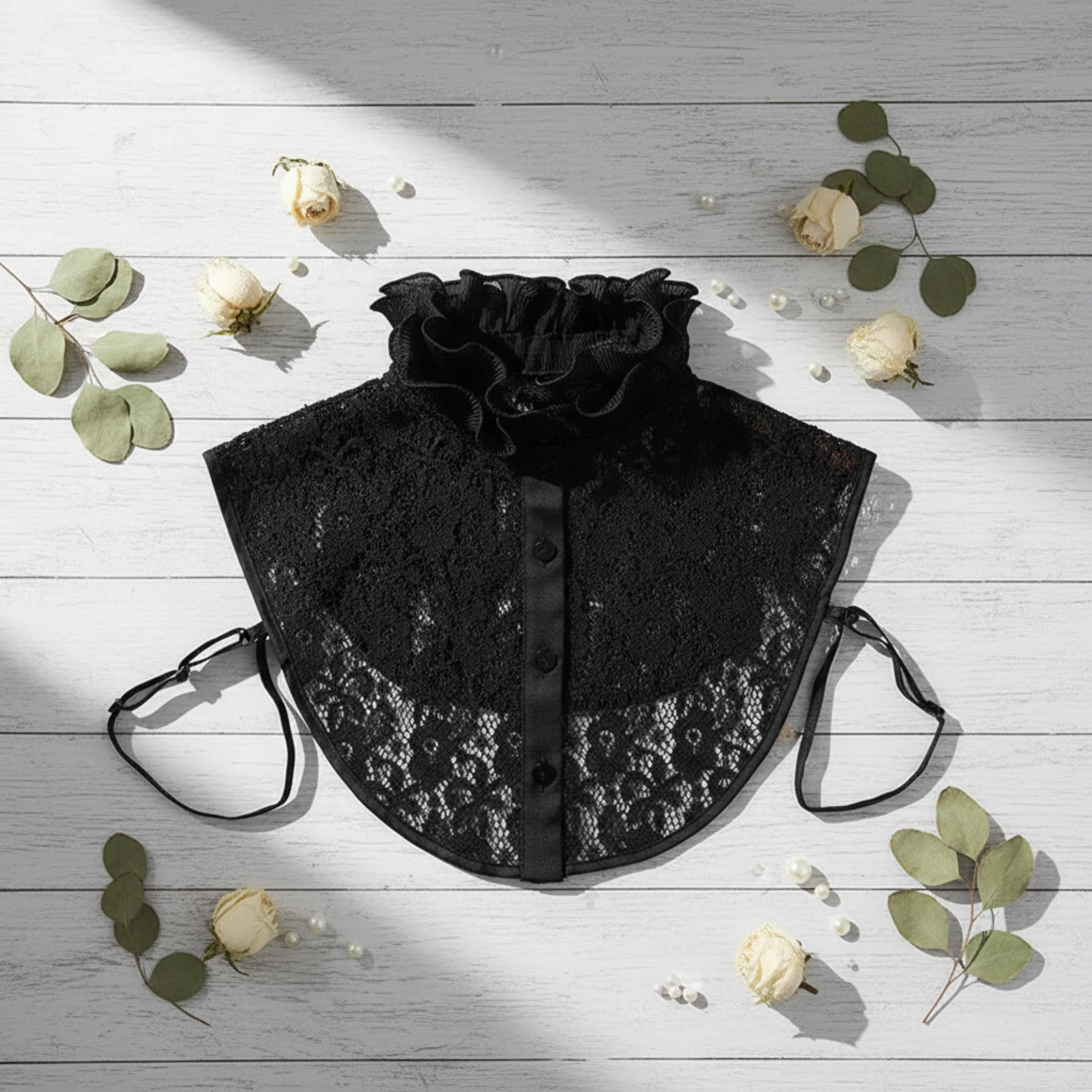 Black lace ruffle collar flat lay with eucalyptus sprig