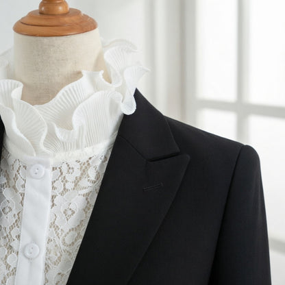 Woman wearing white lace ruffle collar with blazer by window