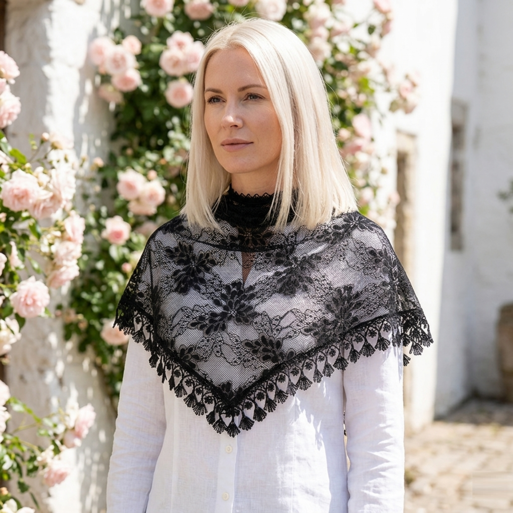Woman wearing dusty rose lace triangle scarf over head in rose garden