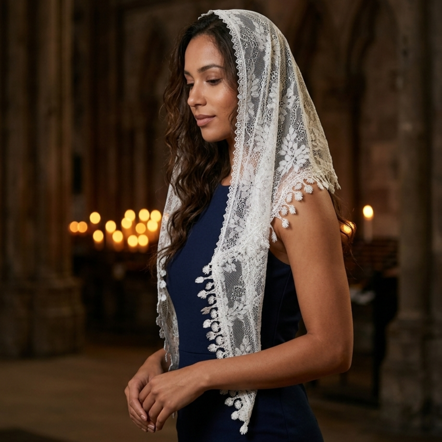 Woman wearing ivory lace triangle scarf as veil in candlelit hall