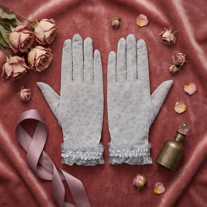 Gray leopard print lace gloves flat lay on burgundy velvet with roses