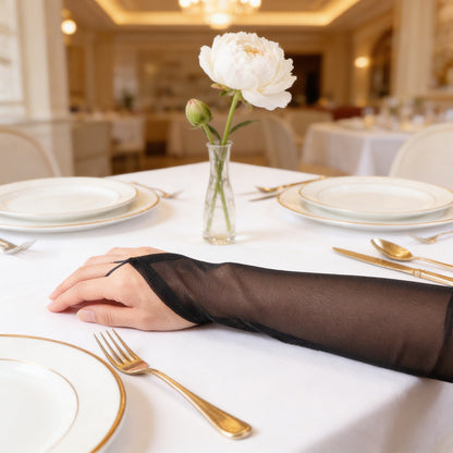Black mesh arm sleeves resting on elegant table setting with white flower