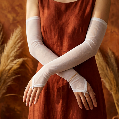 White mesh arm sleeves crossed, flat lay on burgundy fabric