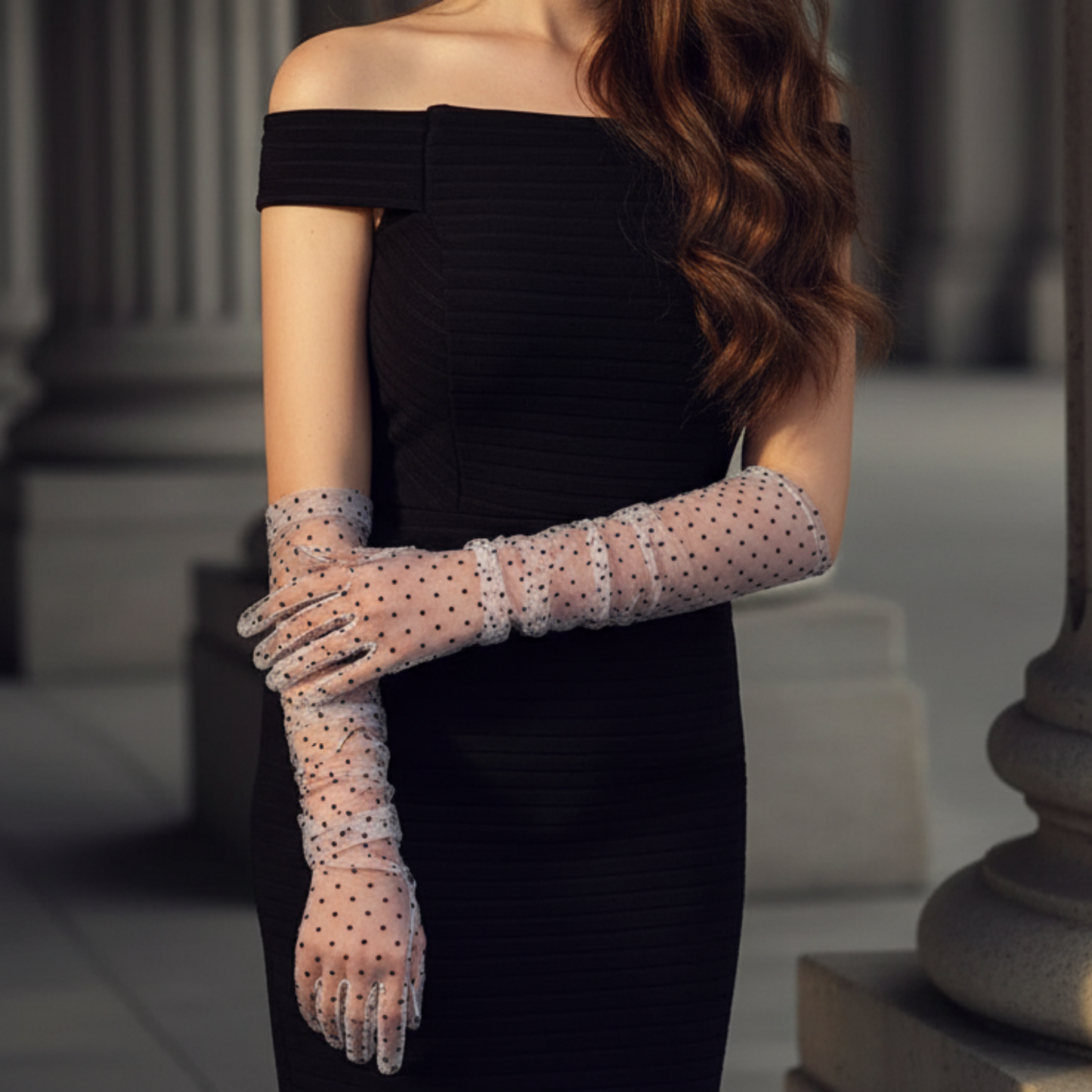 Black polka dot lace opera gloves close-up against column backdrop