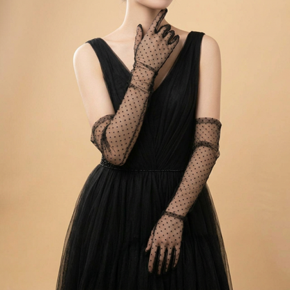 Woman in black dress wearing polka dot lace gloves, ruffled wrist trim
