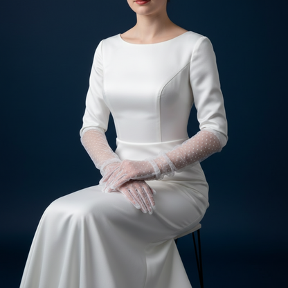 Woman seated in white dress wearing elbow length polka dot lace gloves