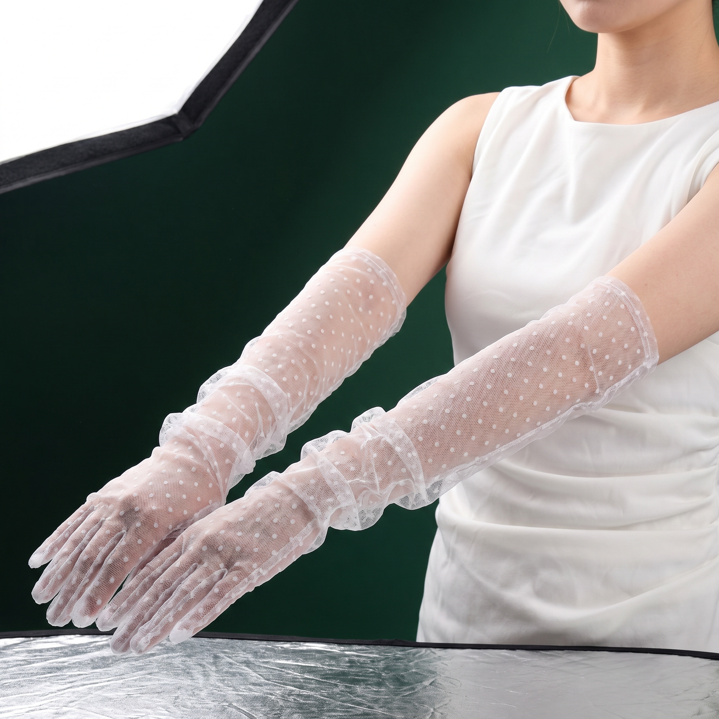 White polka dot lace bridal gloves resting on dark table surface