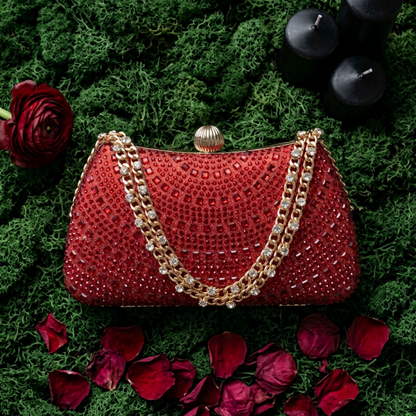 Red rhinestone crystal clutch among green leaves and red roses