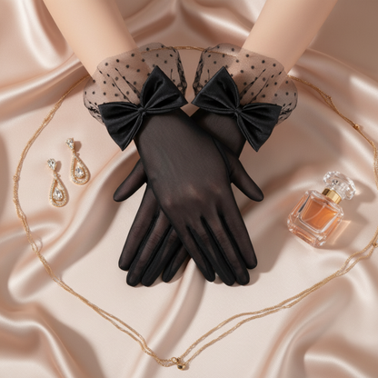 Black sheer mesh bow gloves resting on satin fabric with jewelry