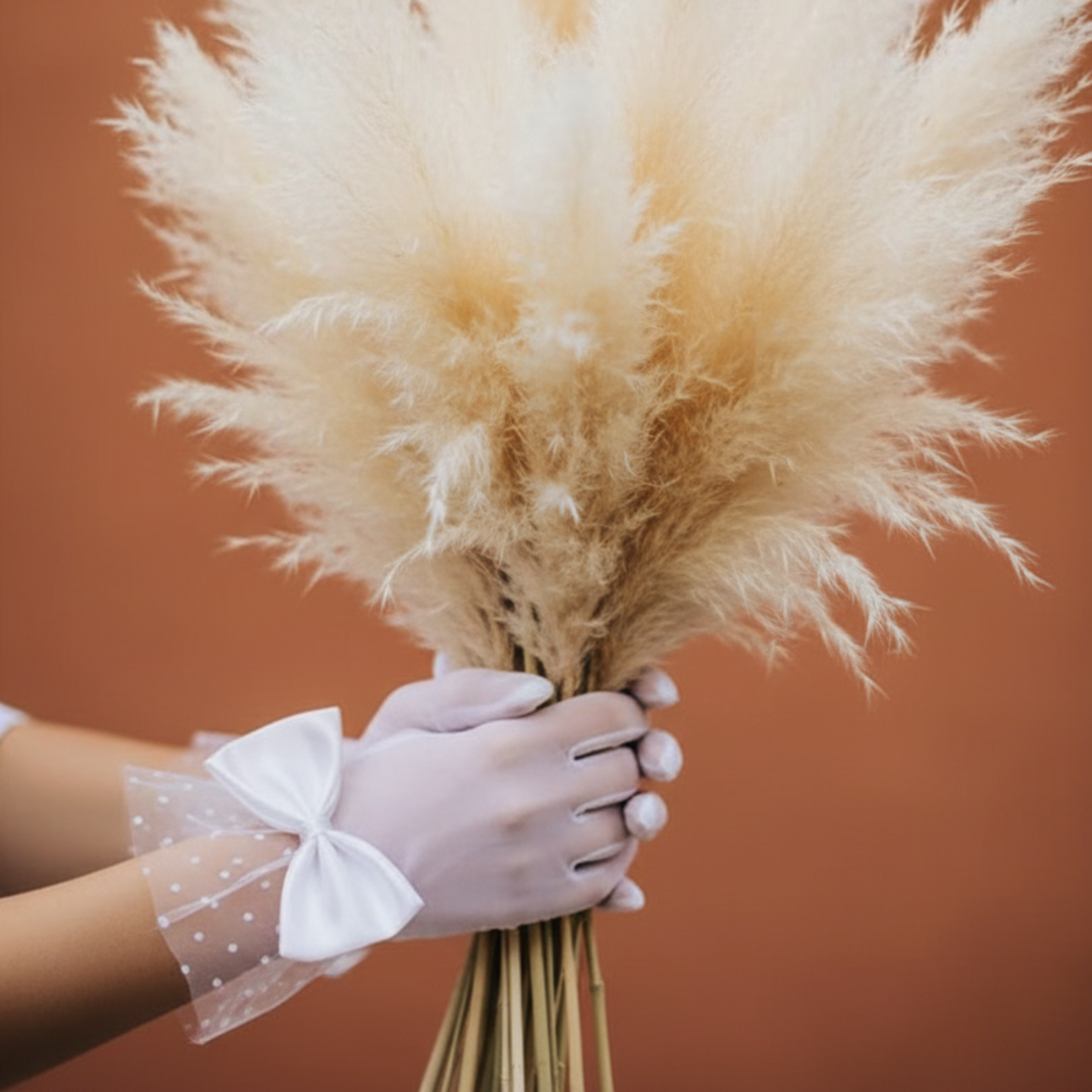 White sheer mesh bow glove holding a dried pampas grass bouquet