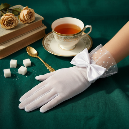 White sheer mesh bow glove with polka dot lace cuff beside a cup of tea