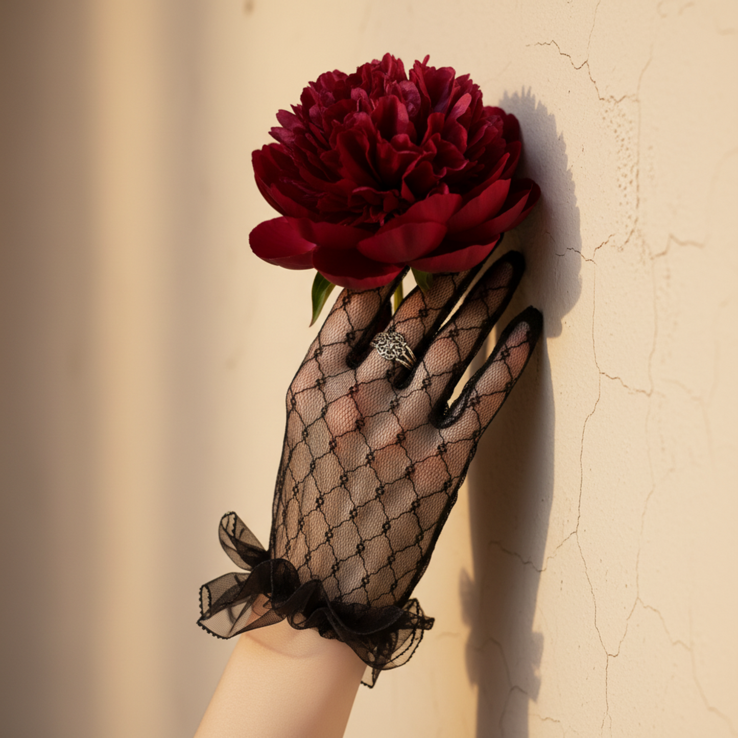 Black lace bridal glove holding a red rose