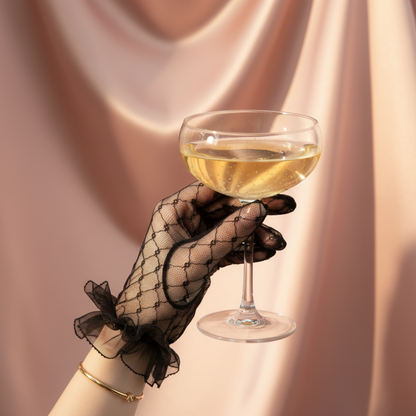 Close-up of black lace bridal glove holding a wine glass