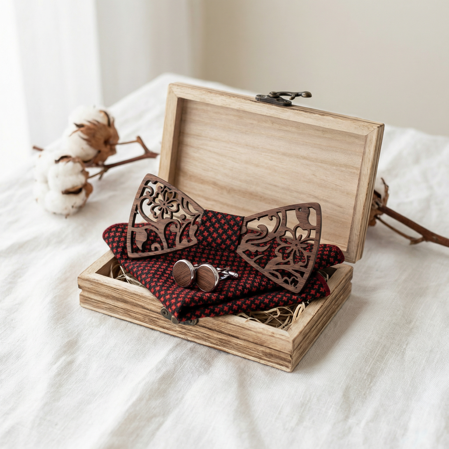 Open wooden gift box with walnut bow tie on white fabric