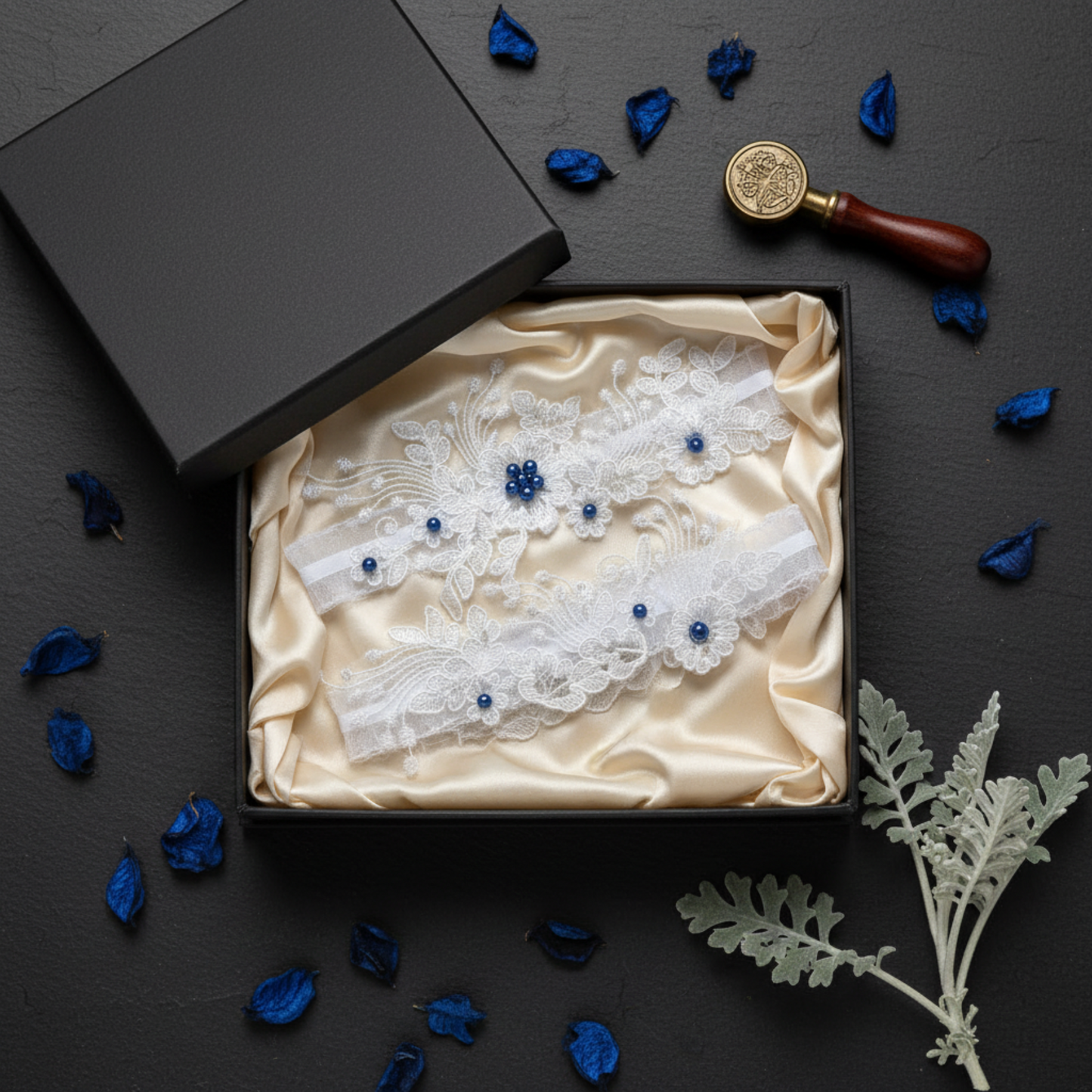 Lace wedding garter set in open gift box with blue petals
