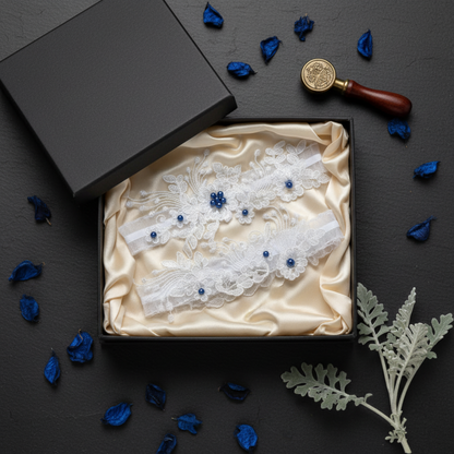 Lace wedding garter set in open gift box with blue petals