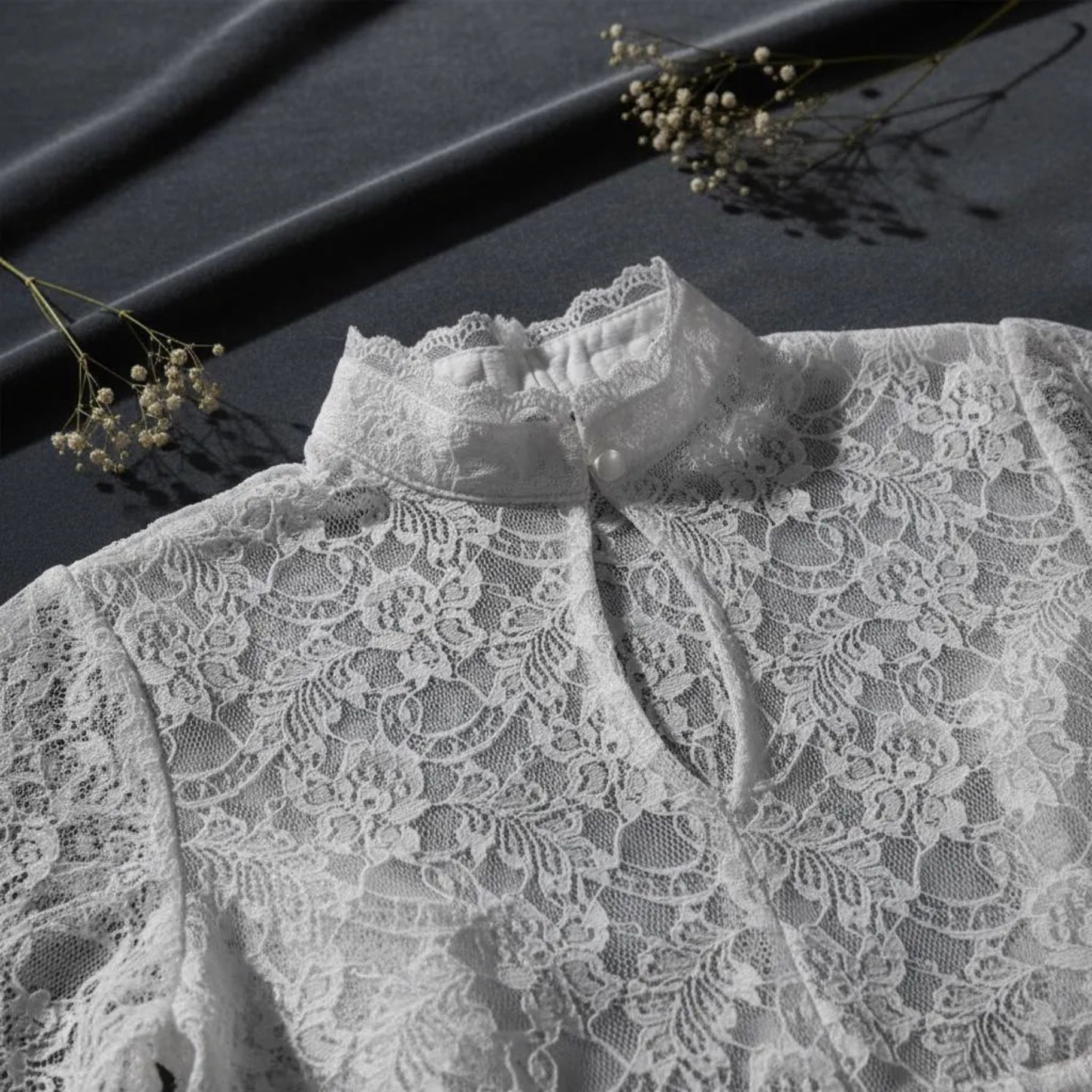 Close-up detail of white floral lace fabric on dark background